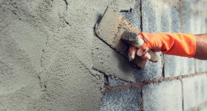 close up hand worker plastering cement on wall for building house